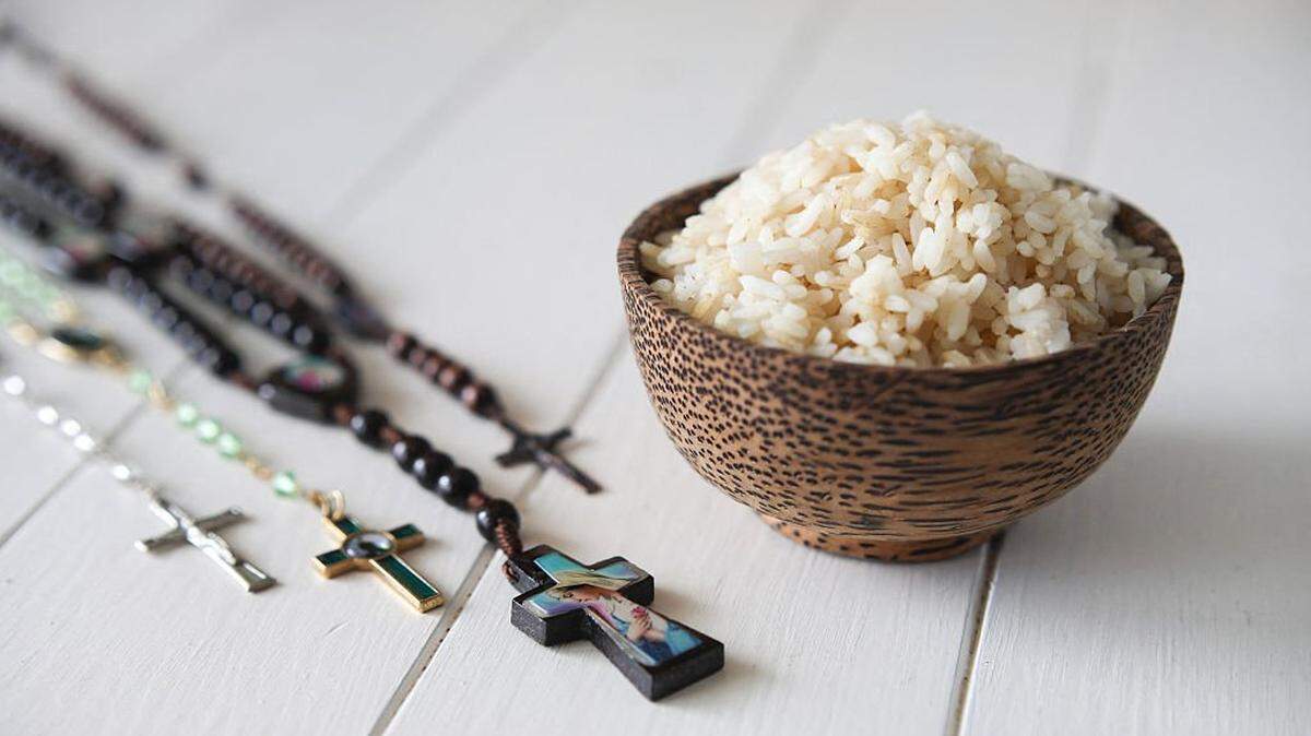 Illustration of a bowl of rice as a frugal meal symbolizing fasting and penance during Lent and Good Friday in Catholicism and Christianity placed next to wooden and metal rosaries bearing the Cross representing the sacrifice of Jesus Christ on Golgotha in Paris on February 23 of 2026. (Photo by Maeva Destombes / Hans Lucas / AFP via Getty Images)