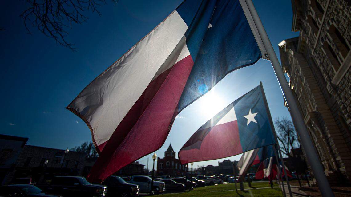 A late afternoon sun lights up Texas flags at the old Hood County Courthouse on the Historic Granbury Square Friday, March 19, 2021.