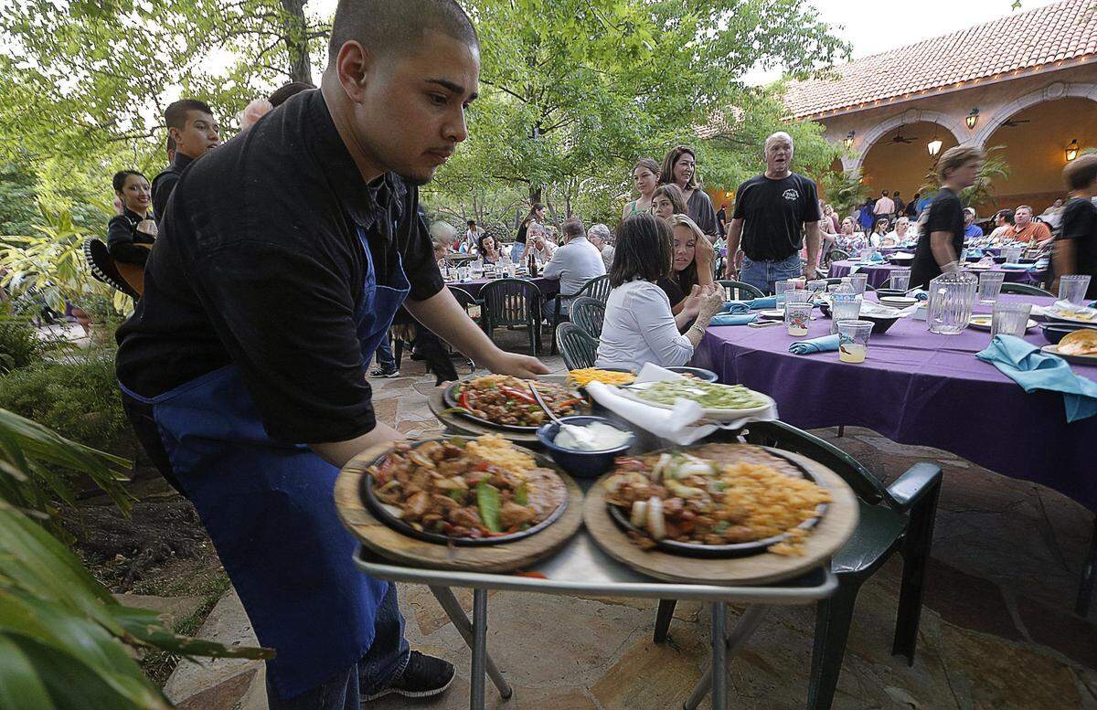 A server carries plates to diners at Joe T. Garcia’s in Fort Worth in 2014.