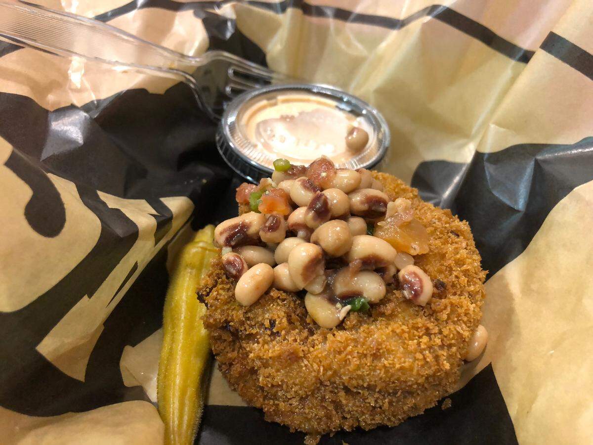 Fernie’s Hoppin’ John Cake with Jackpot Sauce is a fried cake, filled with black-eyed peas, rice, sausage and onions.