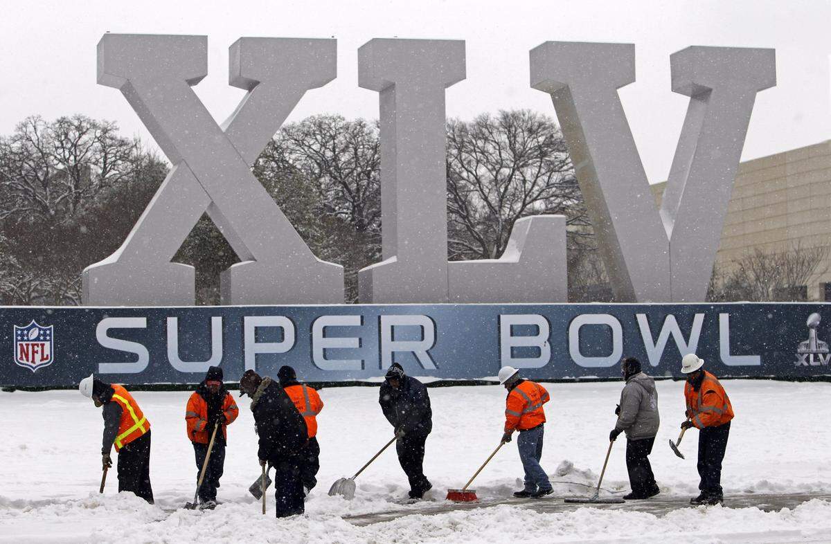 ORG XMIT: ldeluca@dallasnews.com Workers try to clear a sidewalk near the Dallas Convention Center in front of the Super Bowl XLV logo after a haevy early morning snow on Friday, February 4, 2011.  (Louis DeLuca/The Dallas Morning News) ORG XMIT: DMN1102041031531413