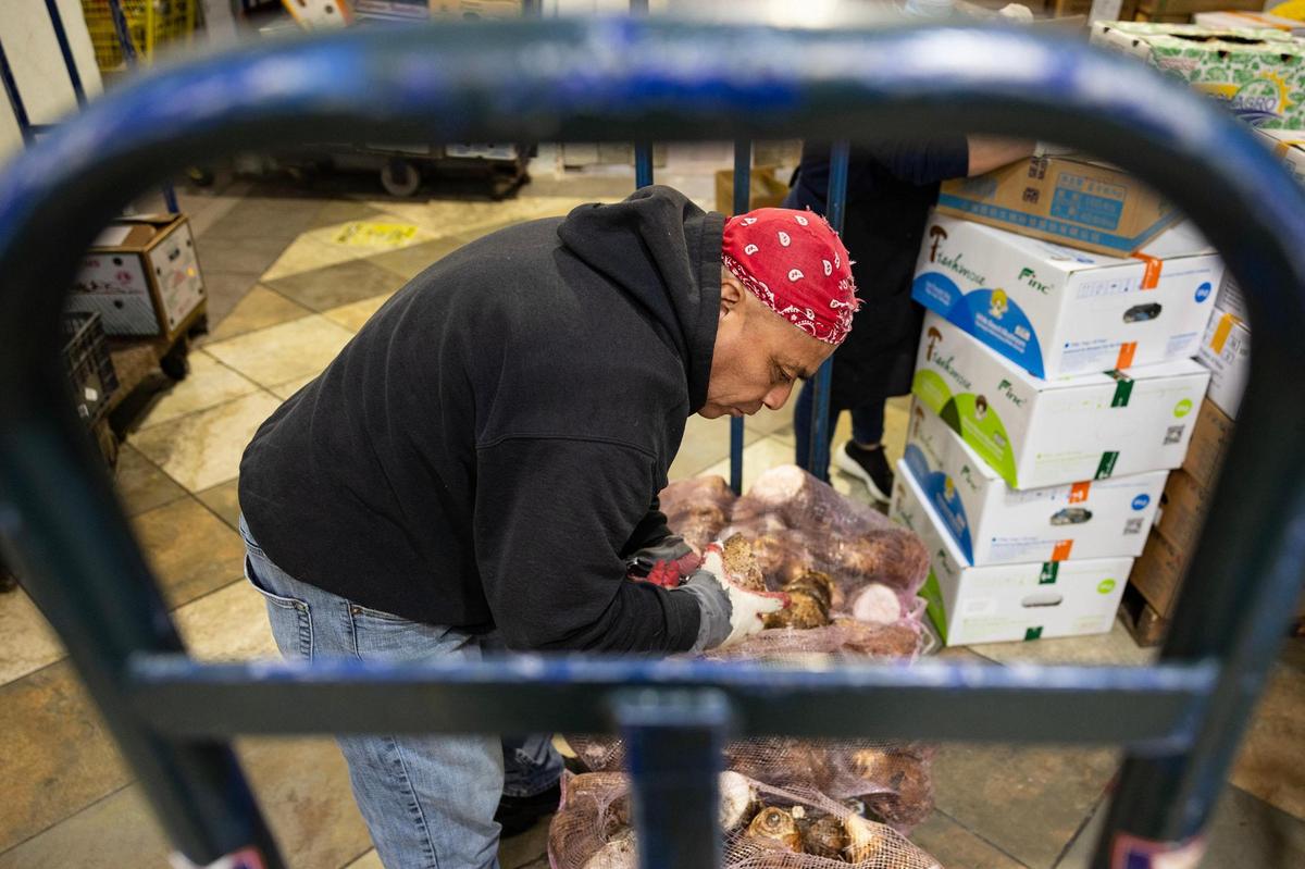 A produce worker who goes by Ciello checks the quality of yucca roots at Nguyen Loi Oriental Supermarket in Haltom City.