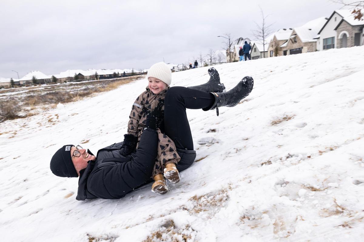 Daniel Boothman sleds down a hill on his back with his son Teddy, 3, in their neighborhood park in southwest Fort Worth on Friday, Jan. 10, 2025.