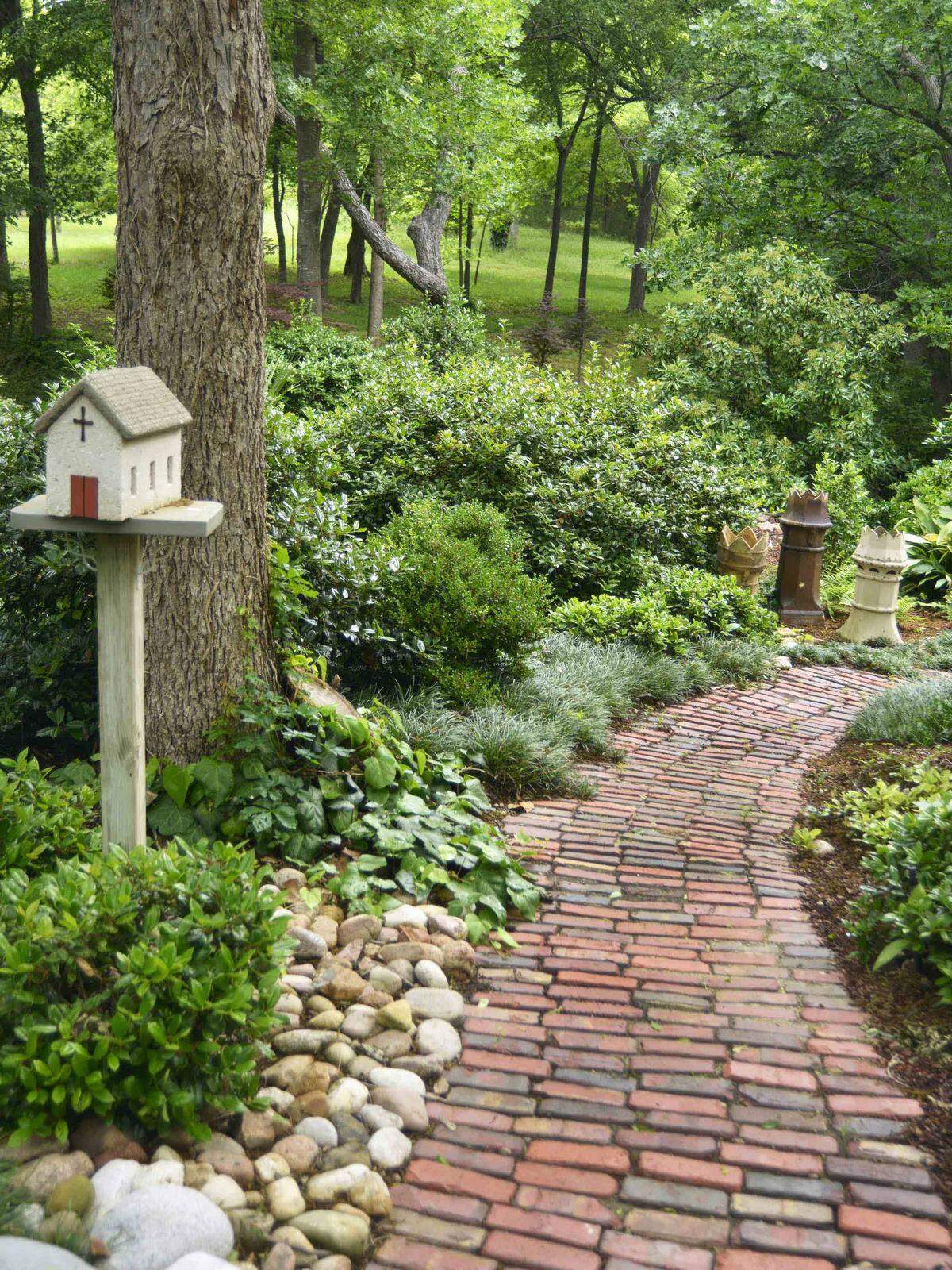 Garden art in the Sperry backyard includes a church on pedestal, antique British chimney pots from pre-WWII, antique brick street pavers from 1900.