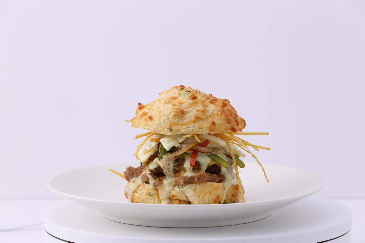 The Spanish Harlem sandwich at Stacks Biscuit House has refried beans, house pork chorizo, sunny side egg, crisp tortilla strips, peppers, onions, cheddar cheese, & bacon jalapeno gravy on a jalapeno cheddar biscuit.