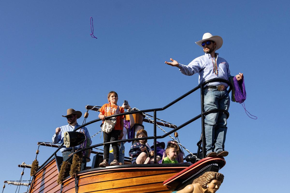 Cody Bates, the Vice President of Operations for the American Hat Company, tosses beaded necklaces from the front of the pirate-ship themed parade float for the 15th Annual Mardi Gras Nocona Style on Clay Street in Nocona on Saturday, Mar. 1, 2025.