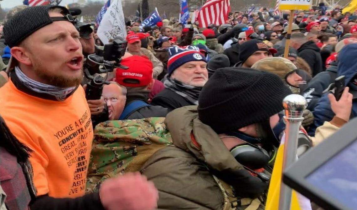 Dustin Ray Williams (far left, in orange) was arrested on felony and misdemeanor charges including obstruction of law enforcement during civil disorder and violence toward officers at the Jan. 6 U.S. Capitol riot.