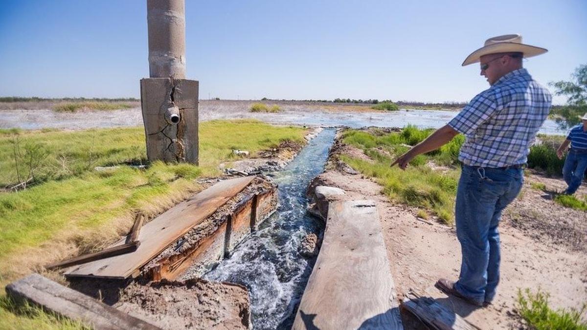 Ty Edwards, assistant manager of the Middle Pecos Groundwater Conservation District, points out brackish water flowing from one of several abandoned wells — originally drilled for oil, but later used for irrigation — that no state agency plans to plug.