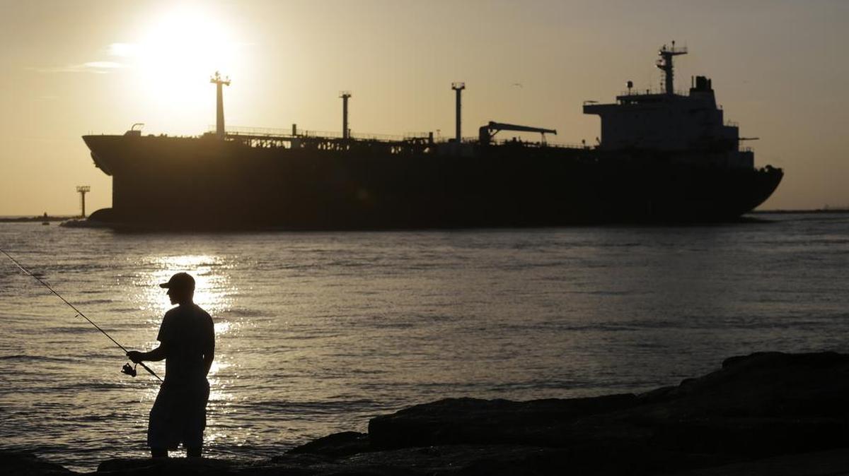 
The price of oil slid Monday, Aug. 3, 2015, as traders braced for softer demand amid an increase in the number of active crude drilling rigs and weak U.S. economic reports. In July, an oil tanker passes a fisherman as it enters a channel near Port Aransas

