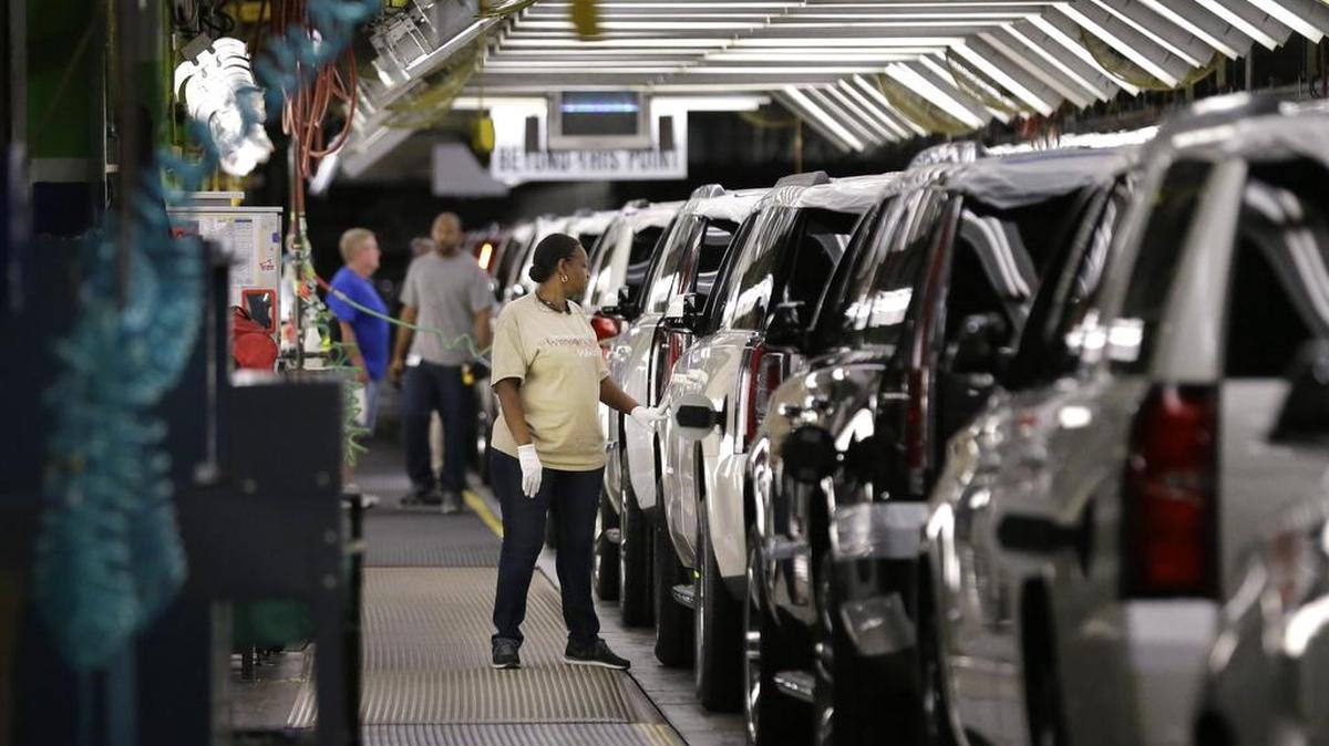An auto worker inspects finished SUVs coming off the assembly line at the General Motors auto plant in Arlington.