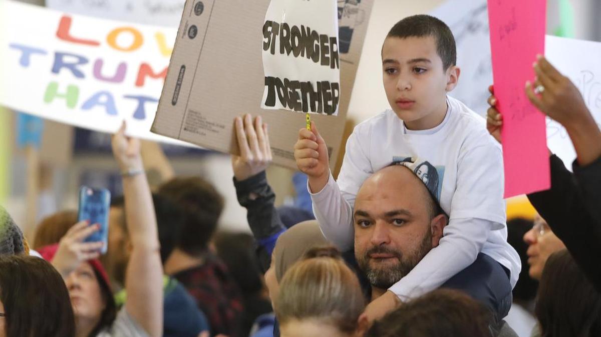 Hazem Elsharkawi, with his son Adam, 8, showed support for the travel detainees held at DFW Airport on Sunday.