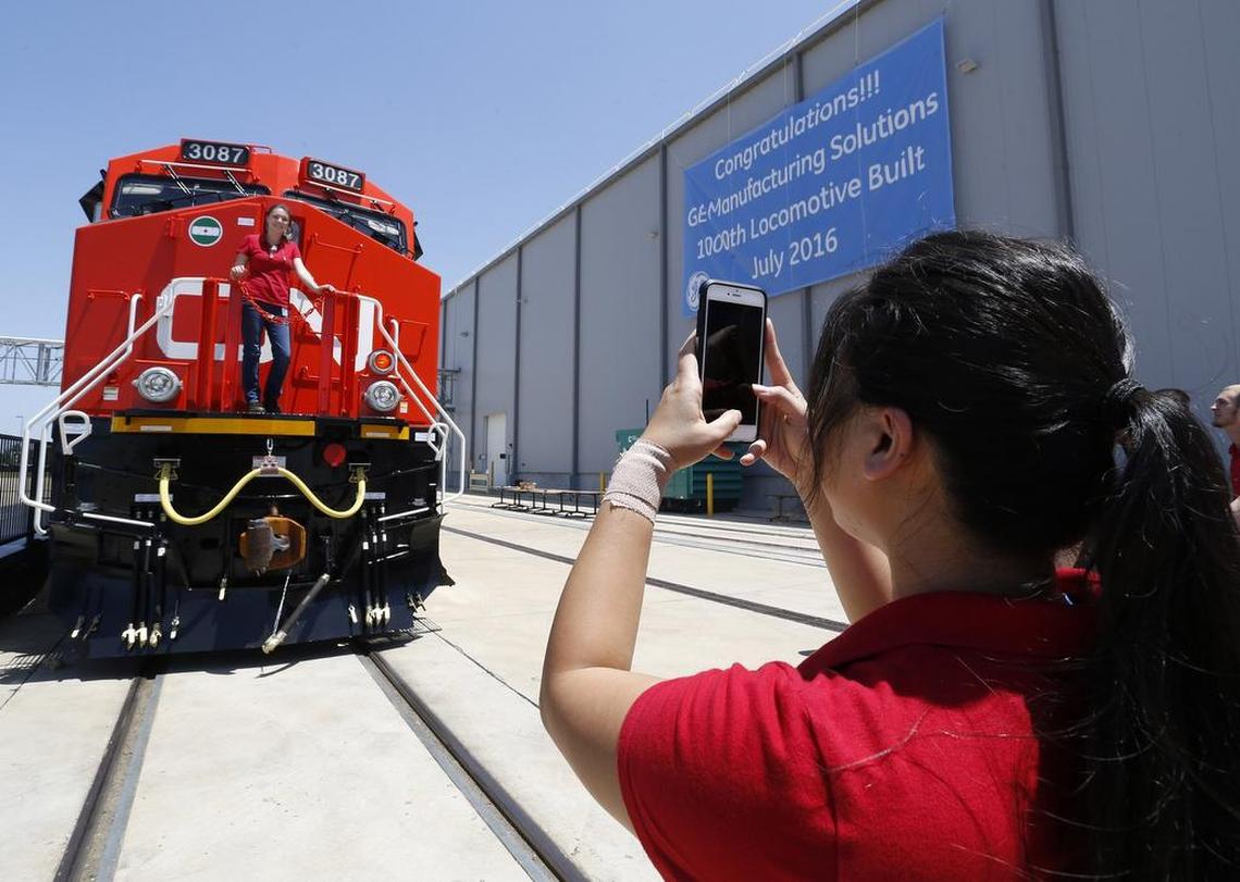 Employee Uyen Pham takes a photo of Lauren Judge posing on the 1,000th engine.