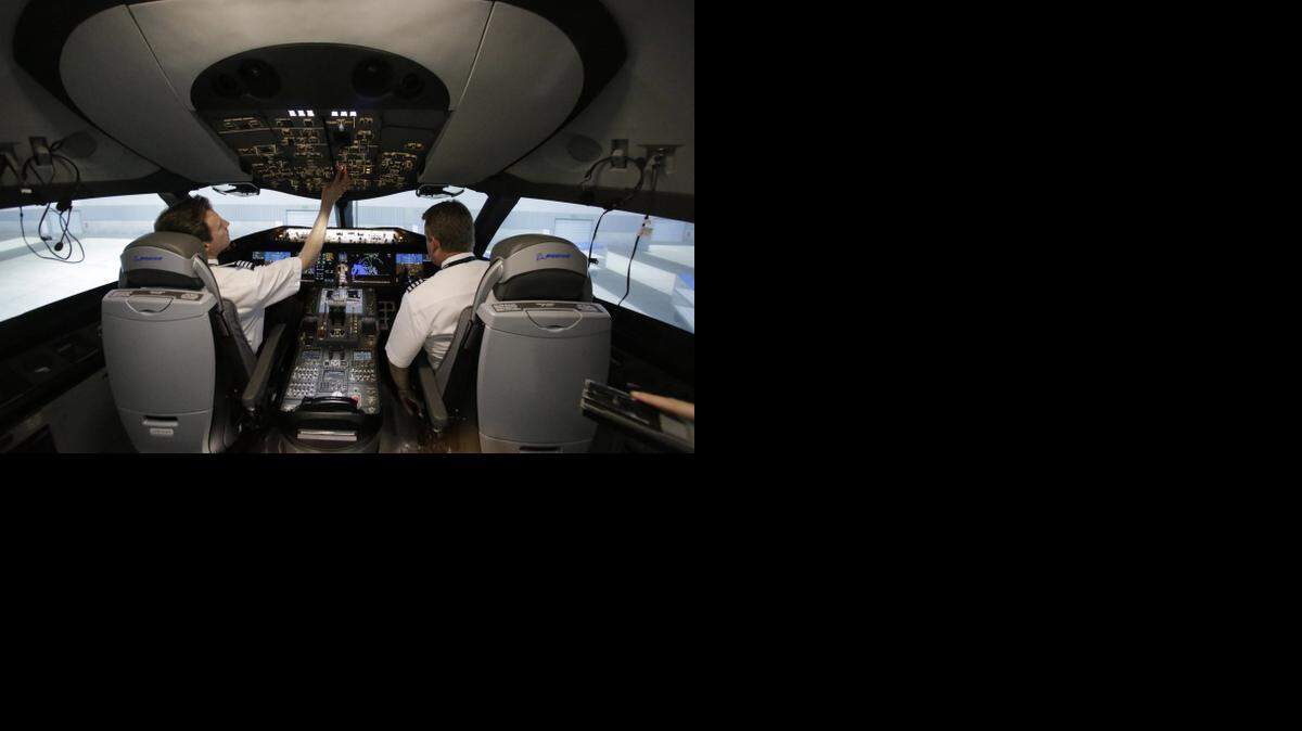 
American Airlines pilots work inside a Boeing 787 flight simulator in Fort Worth showing New York’s JFK airport gate scenery. 
