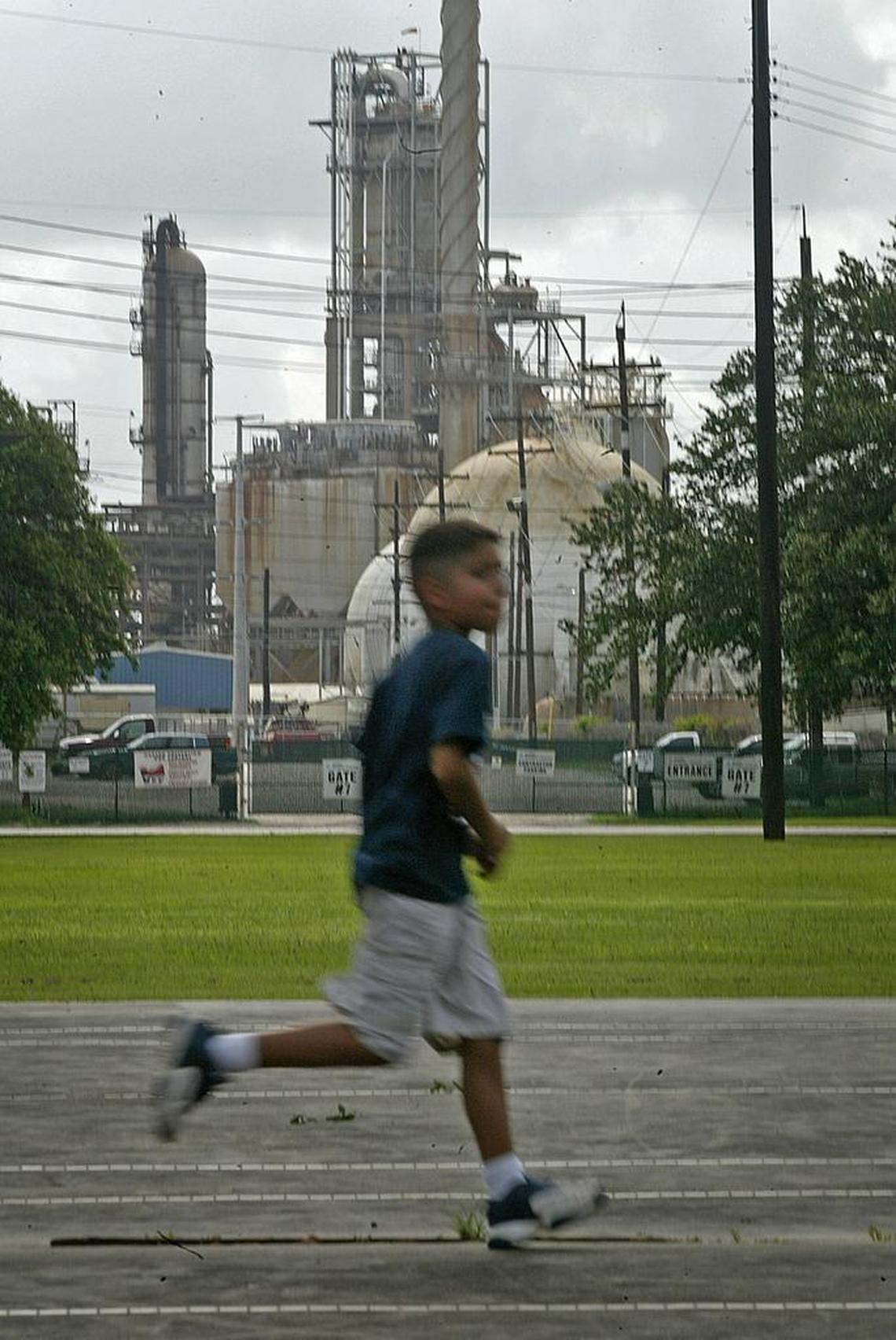 A boy runs across the tennis court in Hartman Park next to petrochemical plants along the Houston Ship Channel in the east part of Houston.