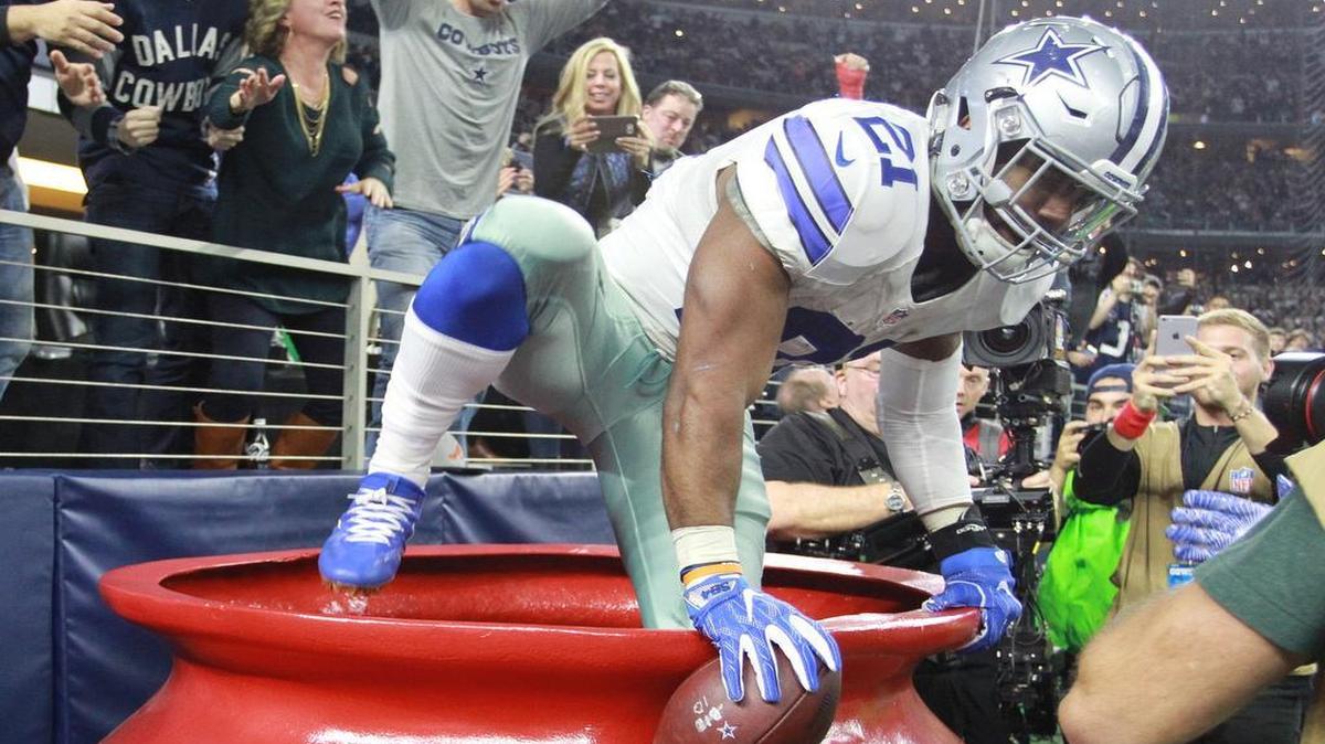 Dallas Cowboys running back Ezekiel Elliott climbs out of the Salvation Army red kettle after a touchdown run in the second quarter against Tampa Bay.