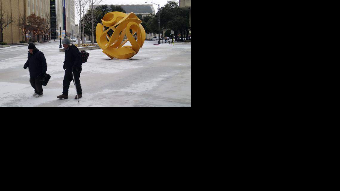 
Donna Newton and Michael Moore make their way carefully across the ice past the Tabachin Ribbon sculpture as they leave municipal court Monday.
