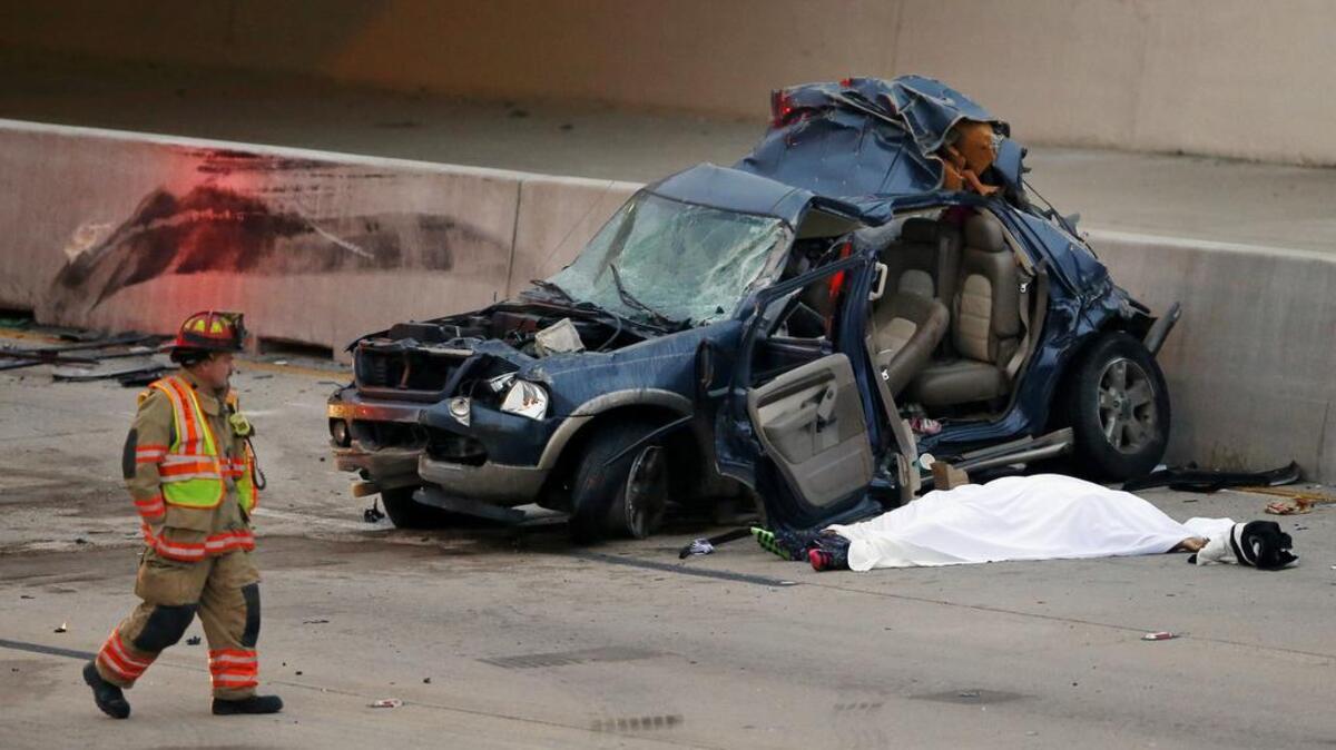 An Arlington firefighter inspects an SUV which was hit by a Greyhound bus in the fast lane on westbound Interstate 30 near Collins St. in Arlington, Texas, killing one, under sheet, in the vehicle early Sunday, Dec. 20, 2015. (Tom Fox/The Dallas Morning News via AP)
