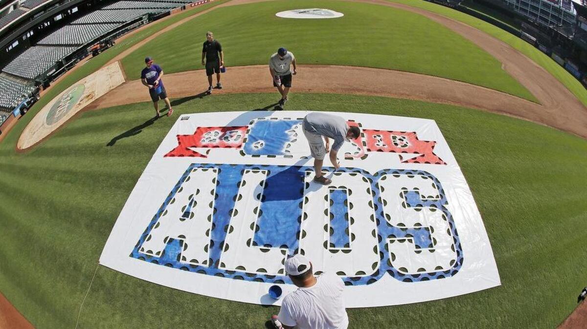 
In preparation for Sunday's first home playoff game, the Texas Rangers grounds crew laid down templates (here) and painted the American League Division Series logo on the first and third baselines at Globe Life Park in Arlington on Thursday. Other preparations were taking place with crews hanging bunting and staff stocking merchandise in the park's souvenier shops.
