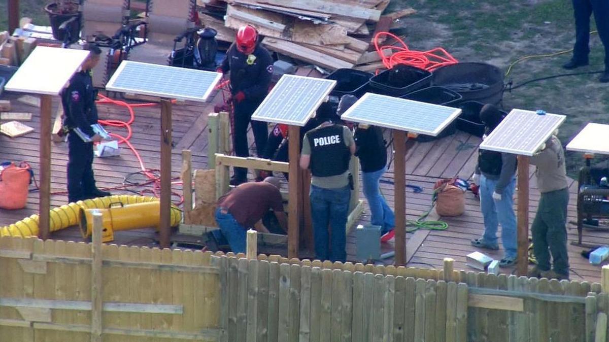Photos taken from WFAA’s helicopter show officers and Arlington firefighters standing above the underground space where marijuana plants were found on Tuesday, authorities say.