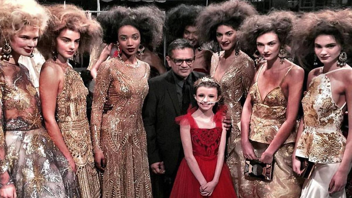 Trinity Moran, 11, of North Richland Hills, poses in her ruby red dress with designer Naeem Khan and professional models at his final show during New York Fashion Week.