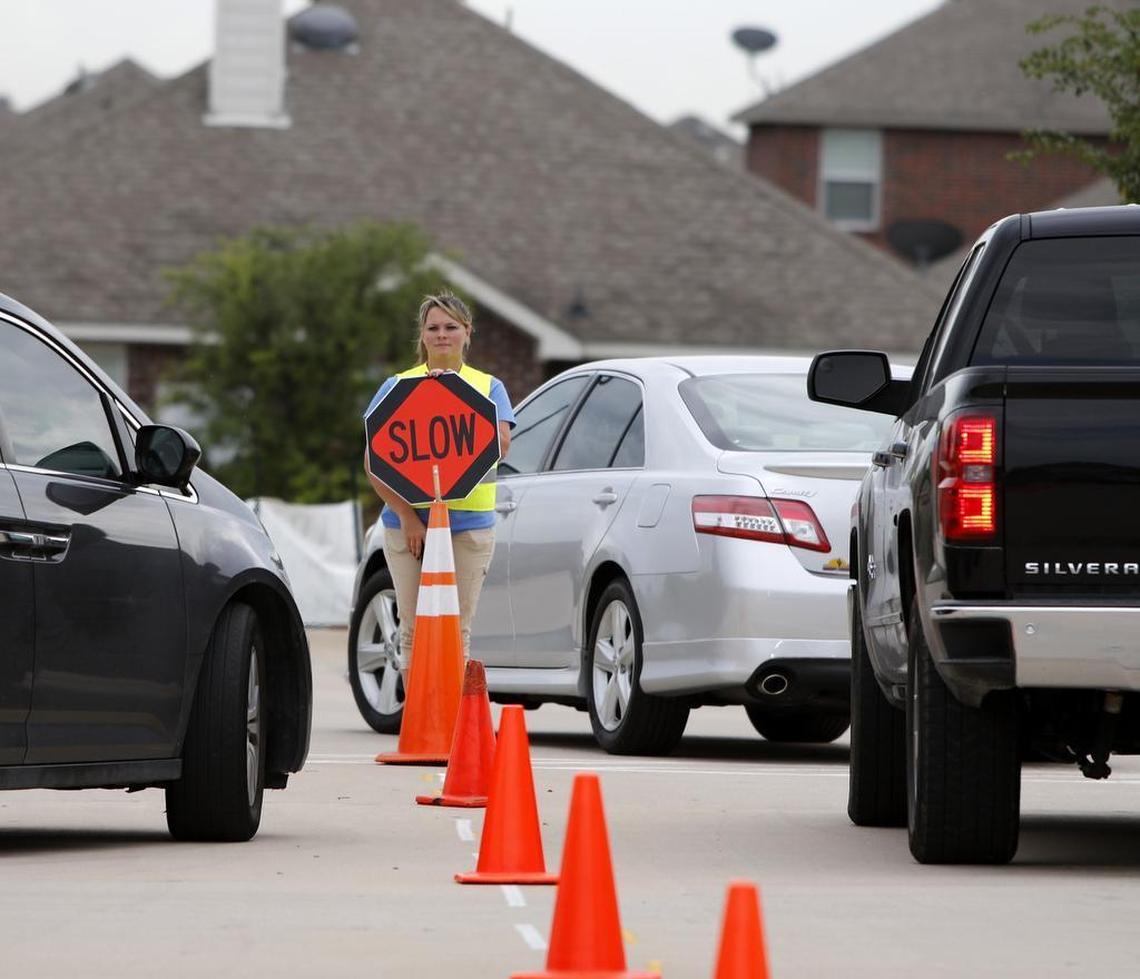 Staff members remind parents to drive slowly after they pick up their children and leave International Leadership Texas-Keller, a K-8 charter school in north Fort Worth.