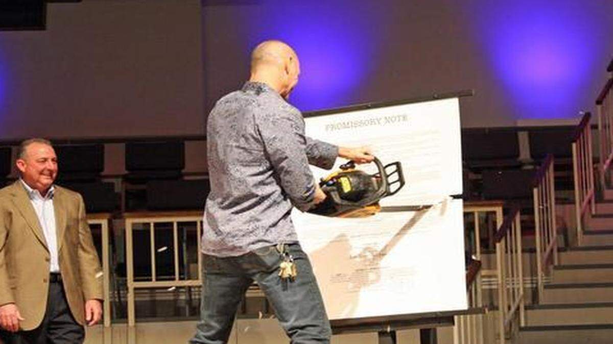 
A church official chainsaws a mock debt document.
