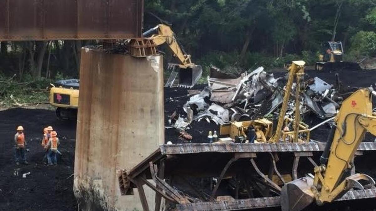 Crews work to clear train wreckage along U.S. 377 in Roanoke on Monday.