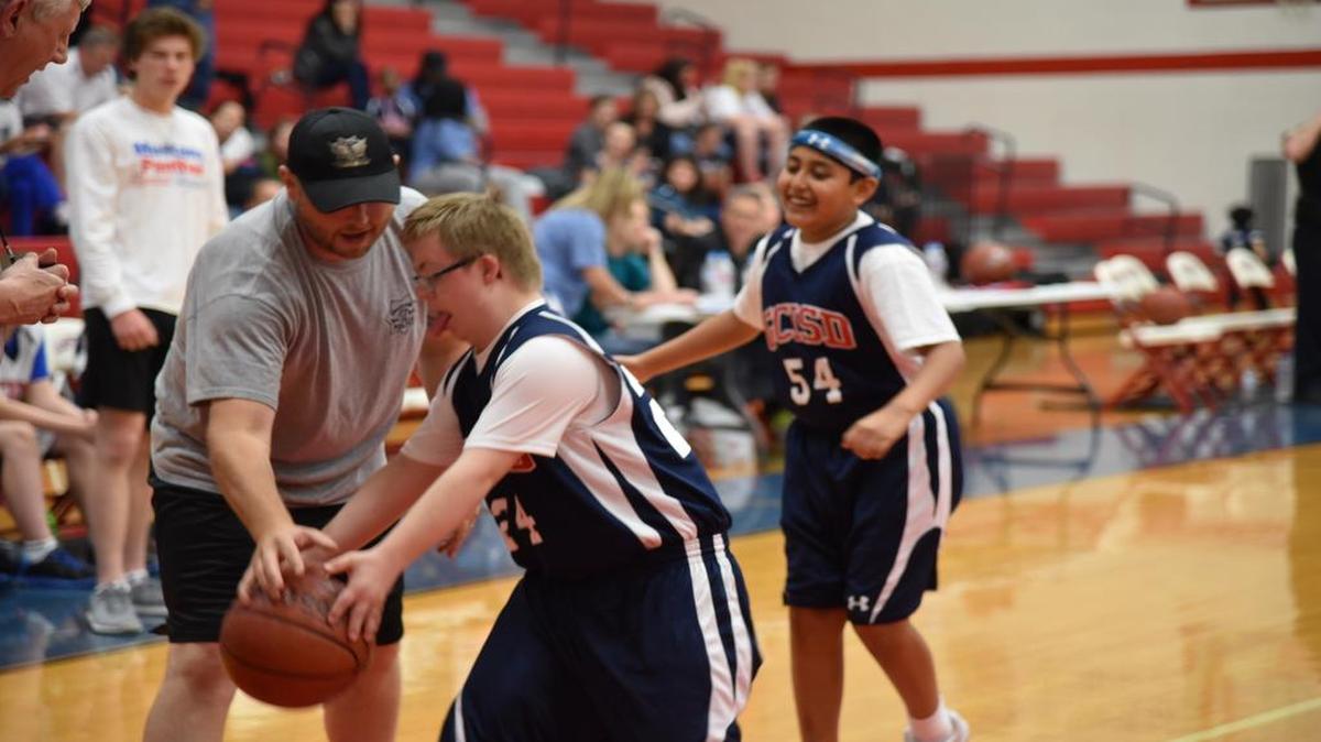 Joseph McTighe, center, tries to keep the ball away from a police officer at the GCISD Special Olympics 4th Annual Triple Threat Shootout. Isaac Montemayor, background, also played on the Olympian team.