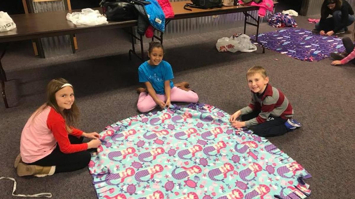 Sophie Adcock, 7; Priscilla Carter, 8 and Liam Adcock, 5 make fleece blankets for the Linus Project, a charity that collects warm blankets to give to children in hospitals.