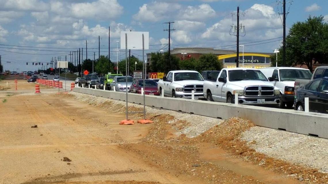 Traffic backs up on Colleyville Boulevard as workers widen the road to six lanes with a center median.