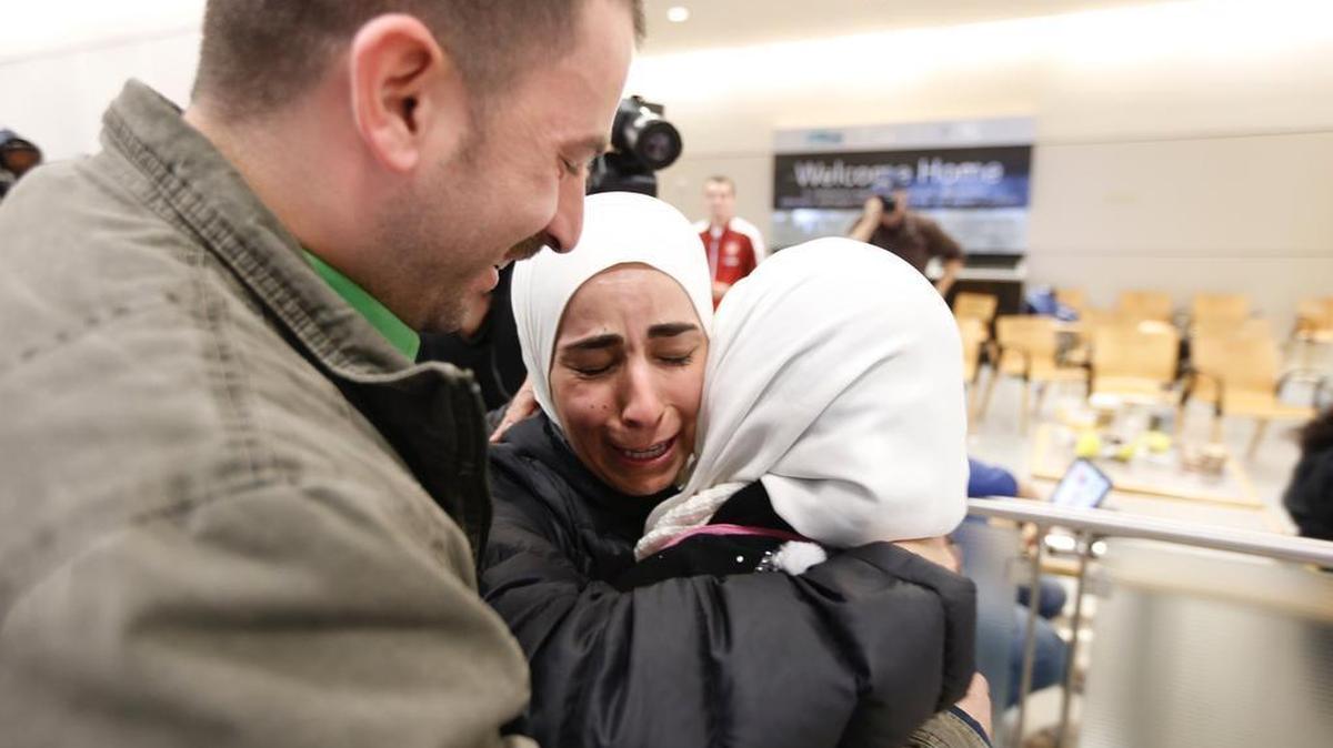 Hisham, left, and Mariam Yasin, center, welcome their mother Najah Alshamieh, 55, from Syria, after immigration authorities released her at DFW Airport.