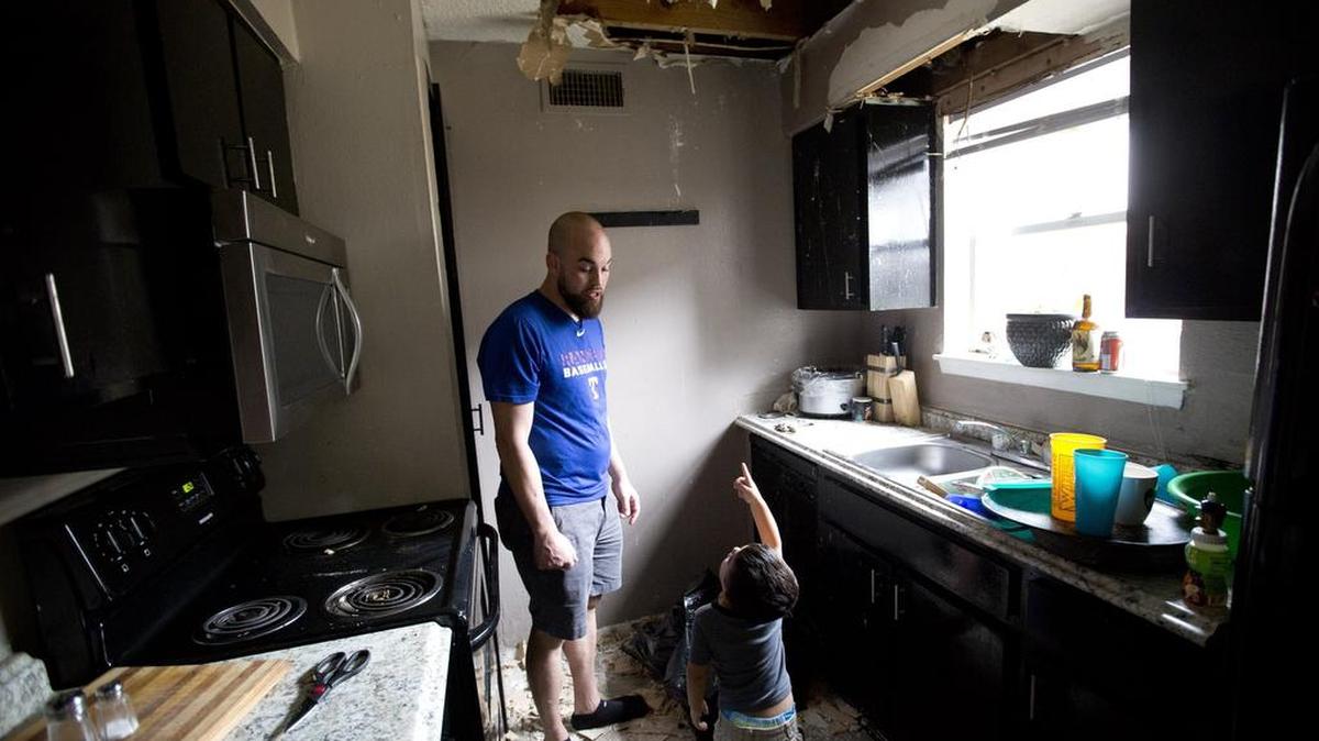 Nathan Barnes with his son Valen, 2, in the kitchen where the ceiling collapsed at the Linbrook apartments in Bedford. The city is suing the owners of the complex for failing to comply with the codes, yet tenants are still living with leaking sewage and caved-in ceilings.