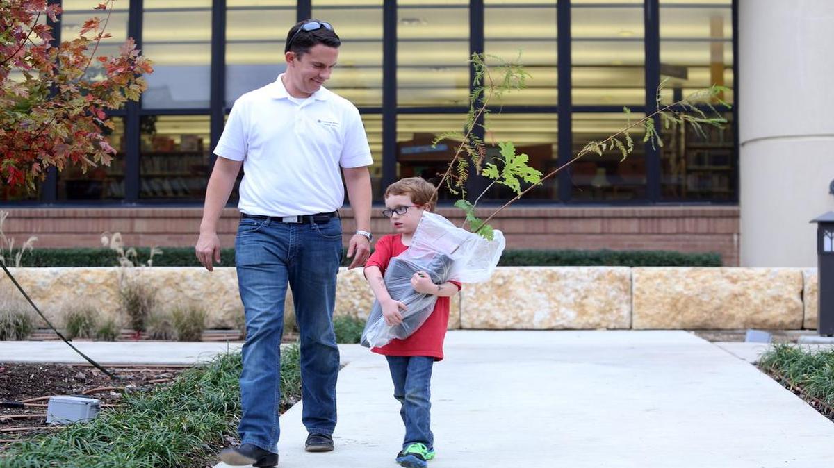 Shawn Holladay, of Grapevine and his son, Parker, 5, with saplings that he helped choose for his family at the annual Grapevine Arbor Day.