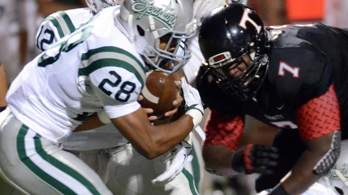 De La Salle's Antoine Custer, left, takes the handoff to head down field as Trinity's Chris Daniels tries to break through the line in the August showdown.
