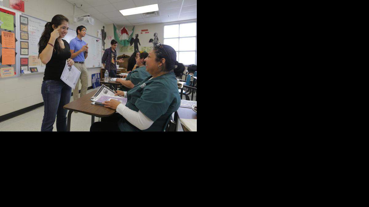 
Student Evelyn Reyes-Marquez, left, works with Teresa Ruiz, right, on English vocabulary as five members of the custodial staff at Trinity High School learn English in a weekly class taught by students who are members of the Spanish Honor Society.
