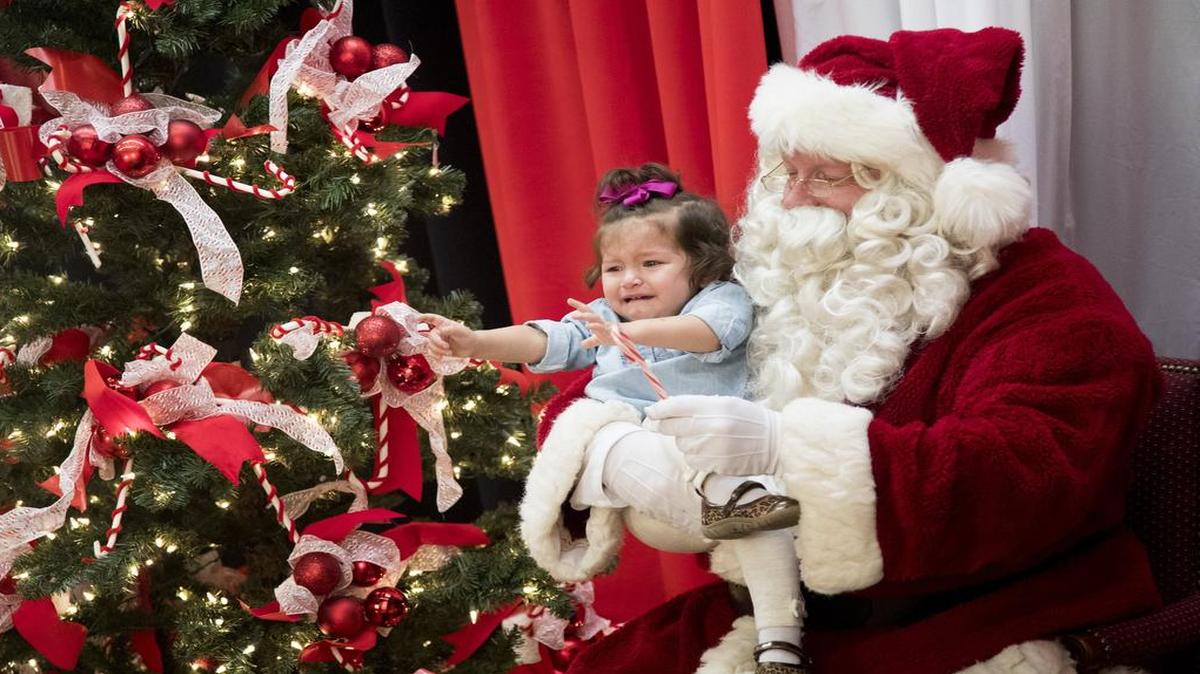Adeline Scheid, 1, reaches for mom while taking a photo with Santa during Breakfast with Santa hosted by the Colleyville Lion’s Club at Colleyville Center.