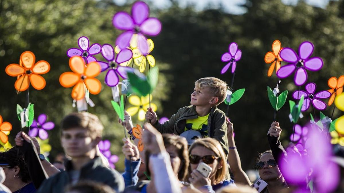 Participants raise flower pinwheels representing the stages of the disease and honoring loved ones during a Walk to End Alzheimer’s event in Grapevine.