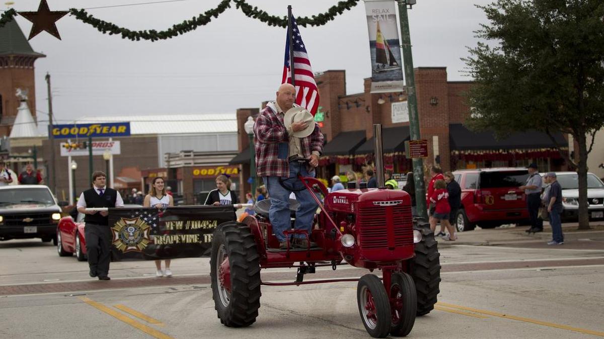 A man on a tractor covers his heart to pay his respects.