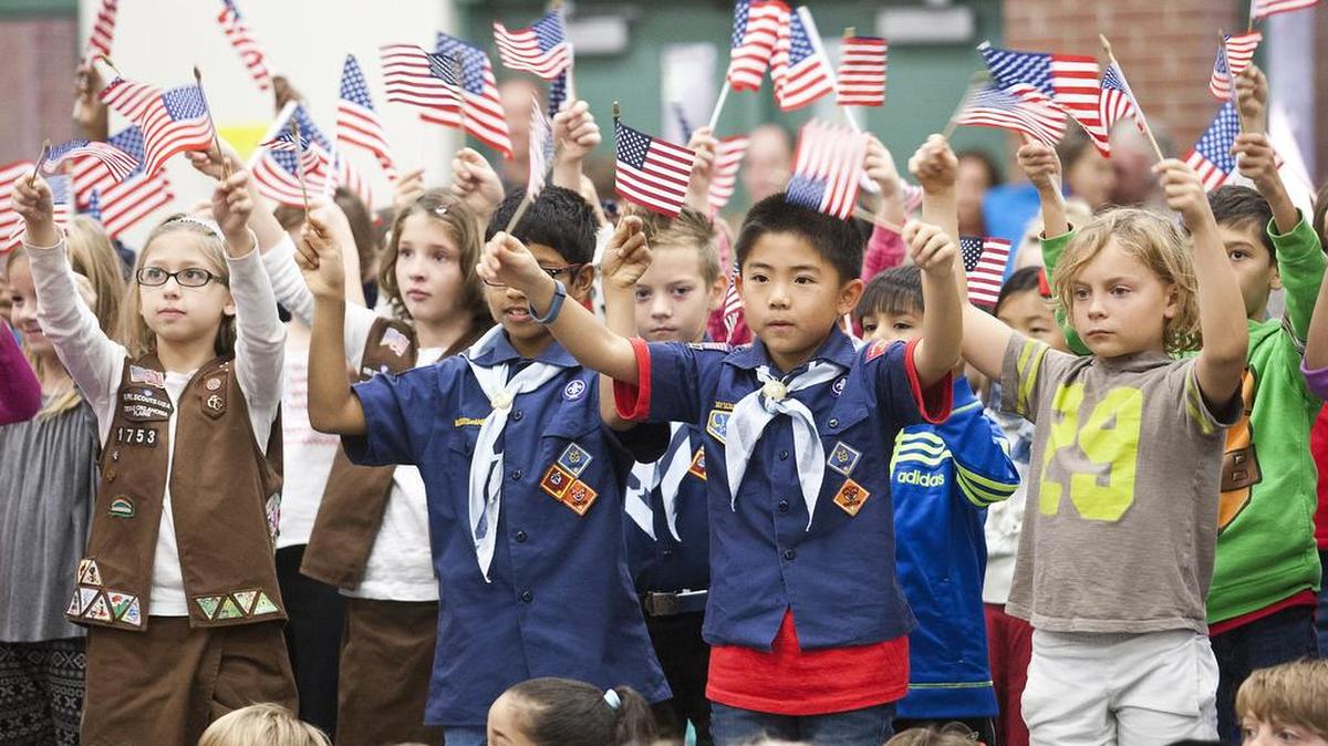 Fourth-graders wave their flags during a 2014 Veterans Day program at Heritage Elementary School in Colleyville.
