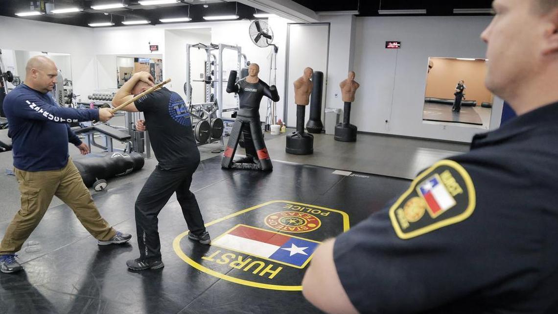 Hurst police officer Jason Delfeld, right, looks on as fefensive tactics instructors Royce Bell, left, and Jim Webster demonstrate how to protect yourself from a surprise attack during a recent training session at the Hurst Police Training Center.