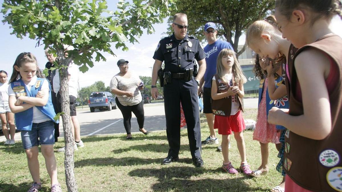 Euless police Cpt. G.L. Landers stands among Girl Scouts during a tree dedication by Troop 1523 for Euless police officer Hofer at the Euless Police Department on Saturday morning.