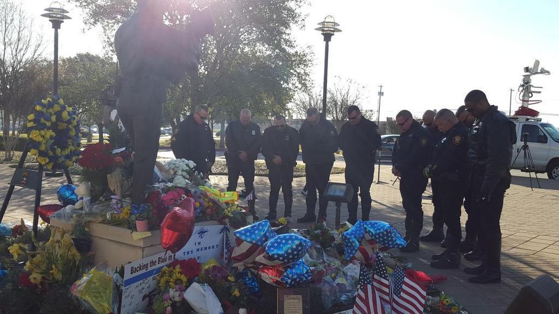 Fort Worth police officers bow their heads at an impromptu memorial to slain Euless officer David Hofer.