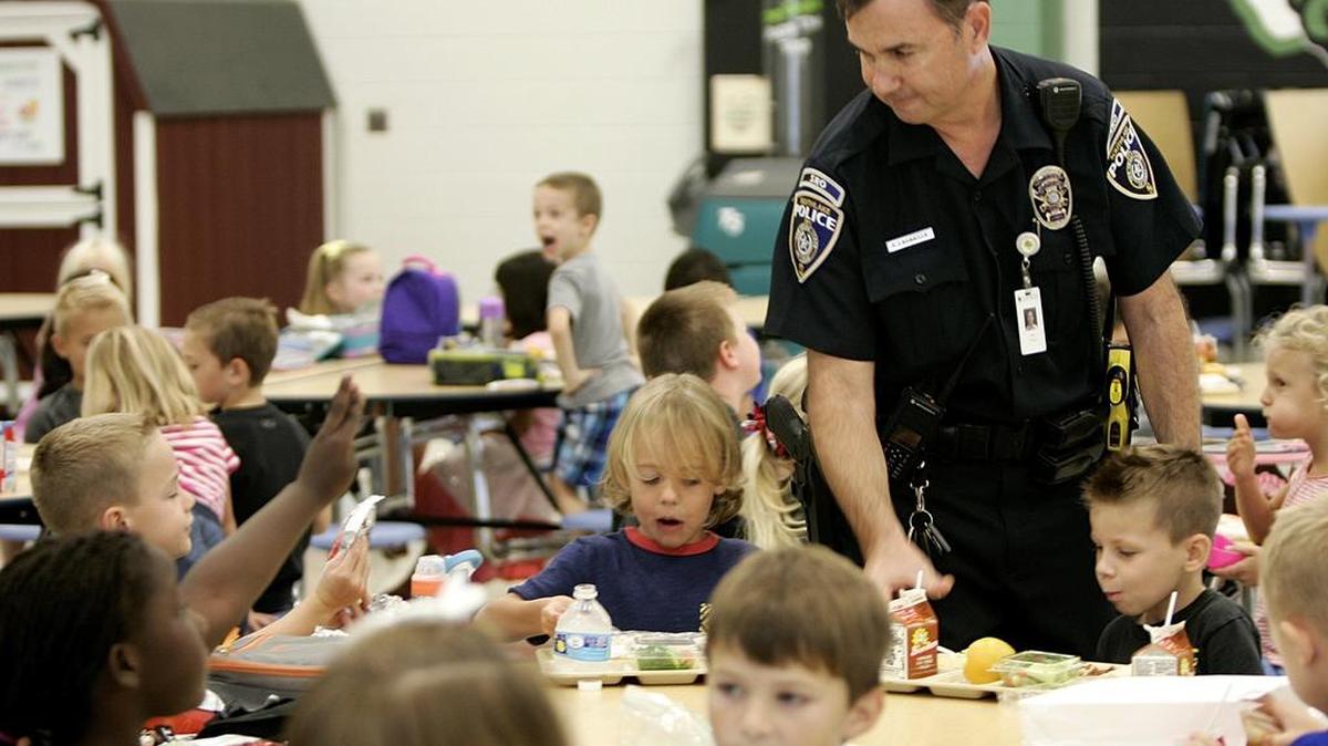 Southlake SRO Frank LaGrassa helps students during lunch in the cafeteria at Walnut Grove Elementary School. Walnut Grove will receive several new staff positions in the fall to handle growing enrollment.