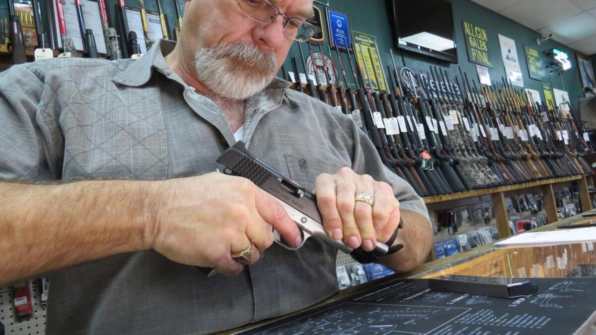 Ed Lewis inspects a handgun at his Euless Guns and Ammo in a January 2015 photograph. Thieves stole 39 handguns from the store early Saturday.