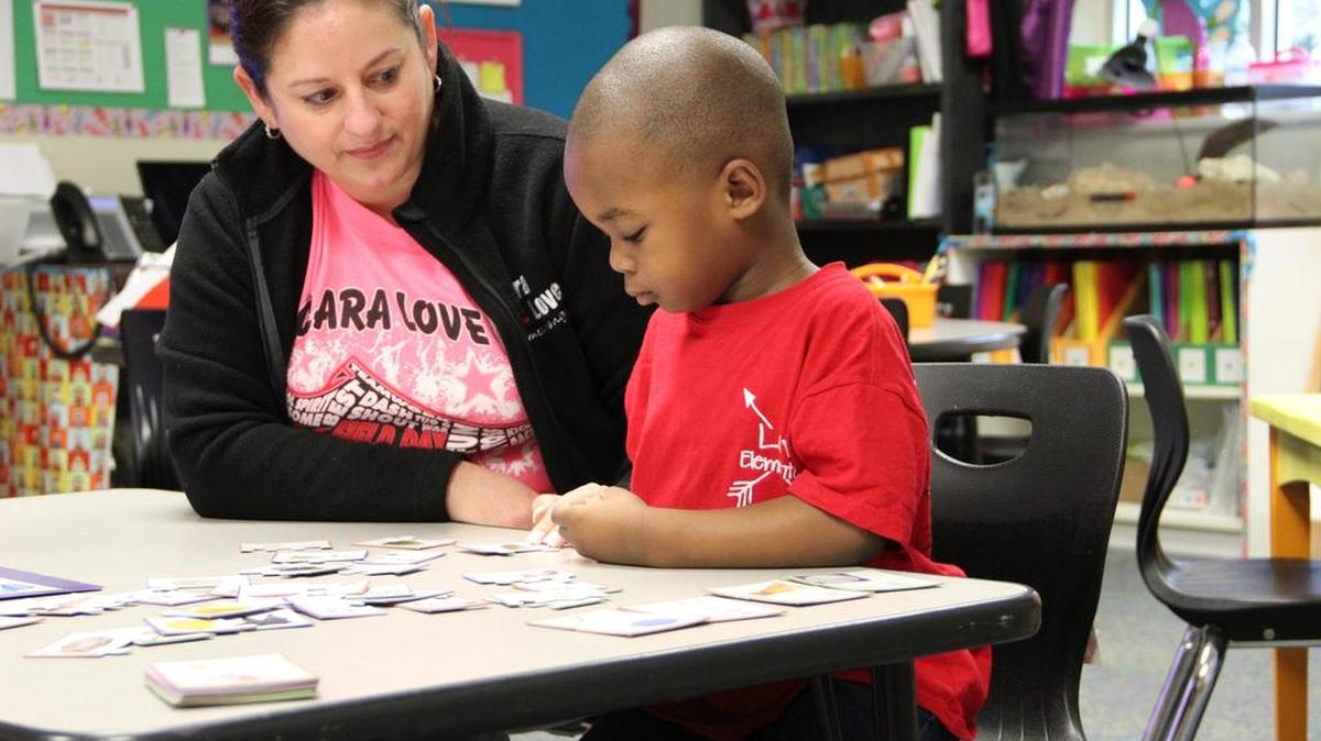 Cheree Black, a pre-kindergarten teacher at Clara Love Elementary School, helps a student with a learning activity.