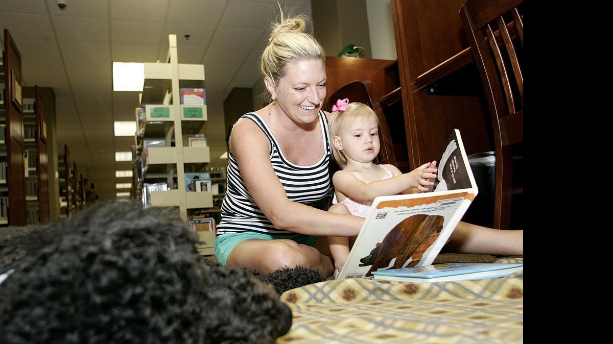 
Jessica Lane and daughter Abbie, 18-mos, read Brown Bear, Brown Bear, What Do You See to six-year-old therapy dog Malbec, a Portuguese Water Dog, at the Southlake Library.
