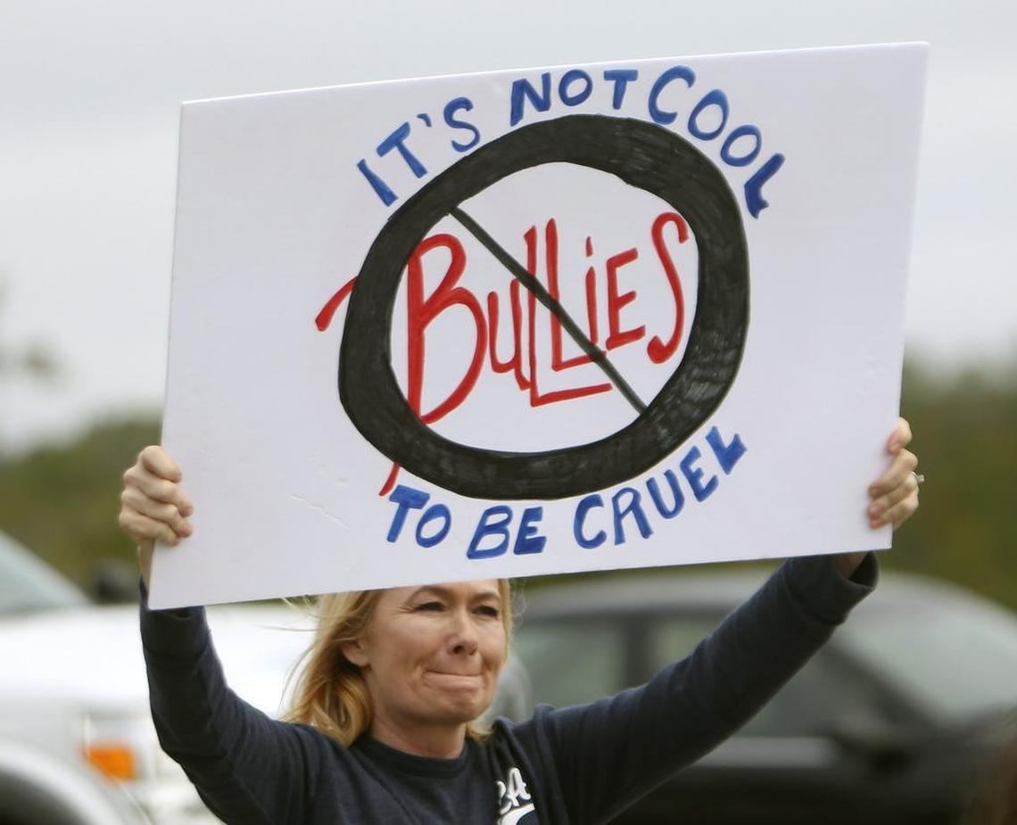 A woman at middle school in Panama City Beach, Fla. carries a sign on Jan. 22 after two 12-year-olds were charged with cyberstalking in connection with the death of a student at the middle school, who police say hanged herself two weeks ago.