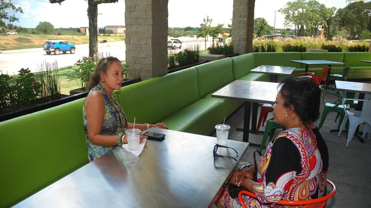 Julia Malveaux, left, of North Dallas, and Phyllis Hodge-Floyd, of Tyler, stopped for a cool drink and conversation on the patio at Lo-Lo's Chicken and Waffles in Southlake. Traffic on Texas 114 buzzes past them in the background.