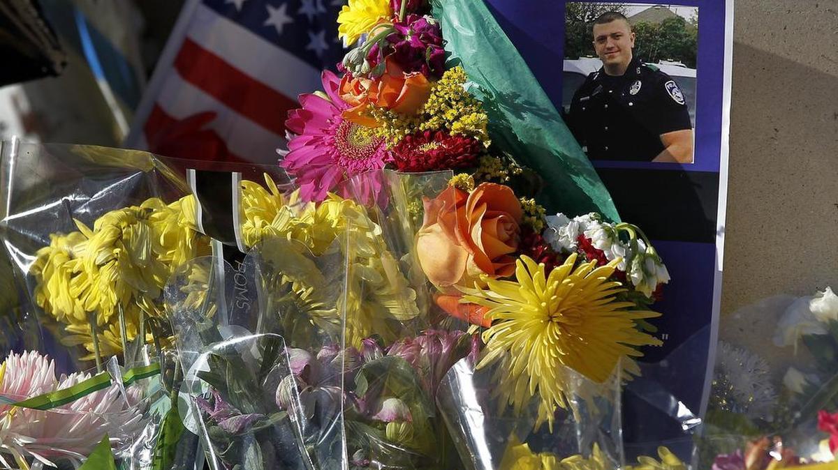 Flowers were placed at the base of a statue at the Euless police station to serve as a memorial to officer David Hofer.