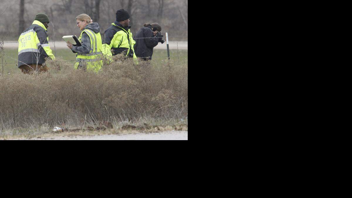 
Investigators walk the fence line along Dirks Road, the site where the body of a woman and child were found Tuesday morning.
